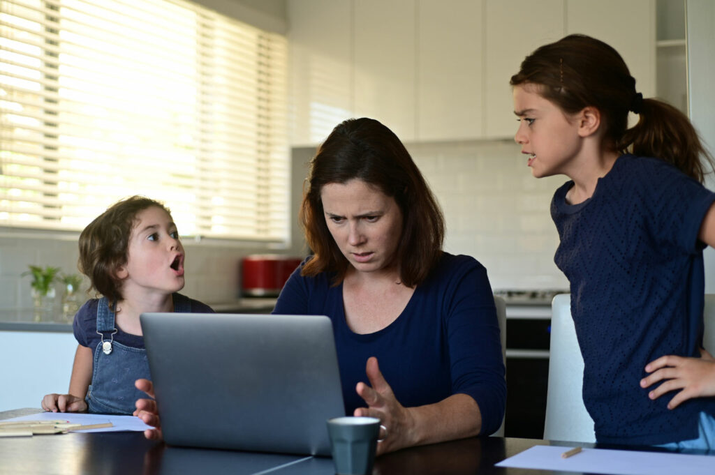 A woman and two girls are looking at a laptop.