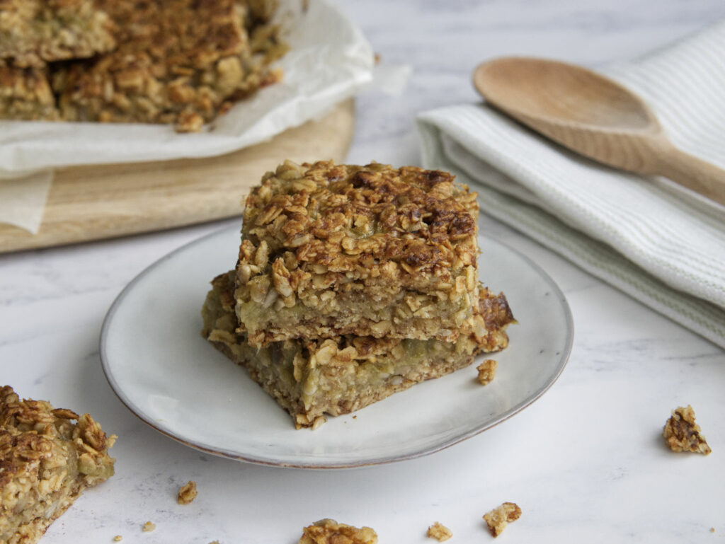 A stack of oatmeal bars on a plate with a wooden spoon.