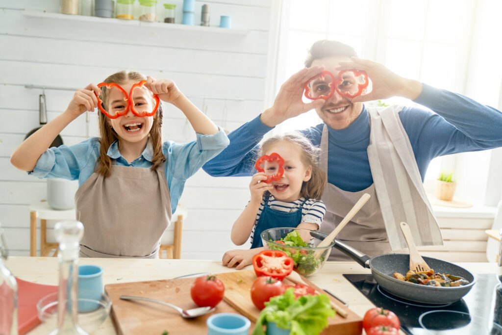 Father and two daughters cooking a healthy meal at home