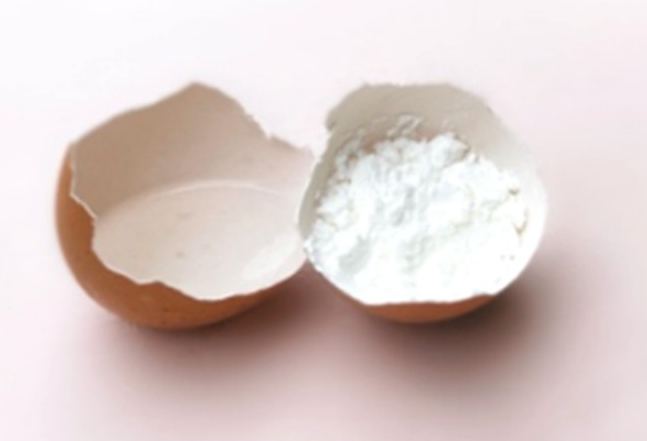 A brown eggshell split in half is shown on a light surface; one half contains cornflour.