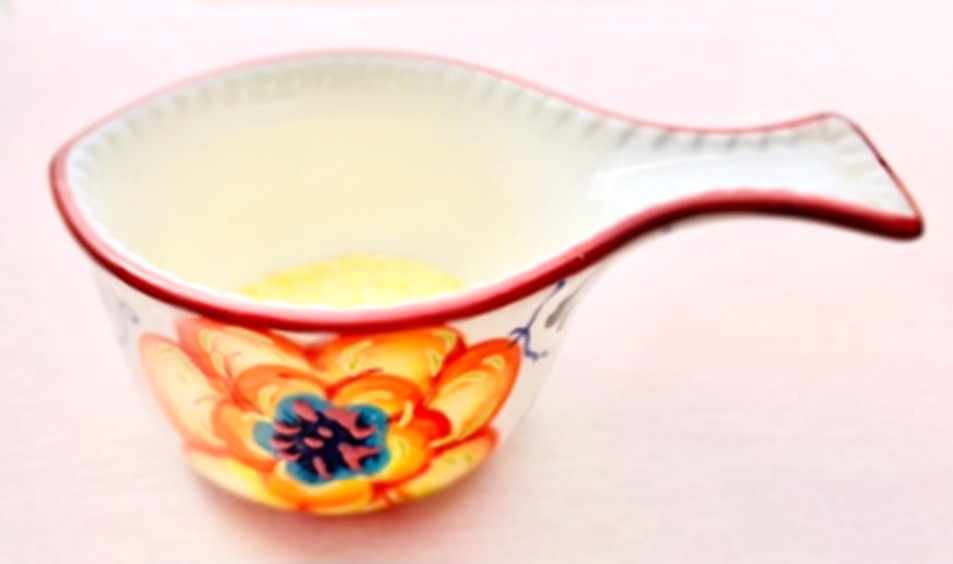 A ceramic measuring cup shaped like a fish, decorated with a bright orange and blue floral pattern, contains liquefied gelatine